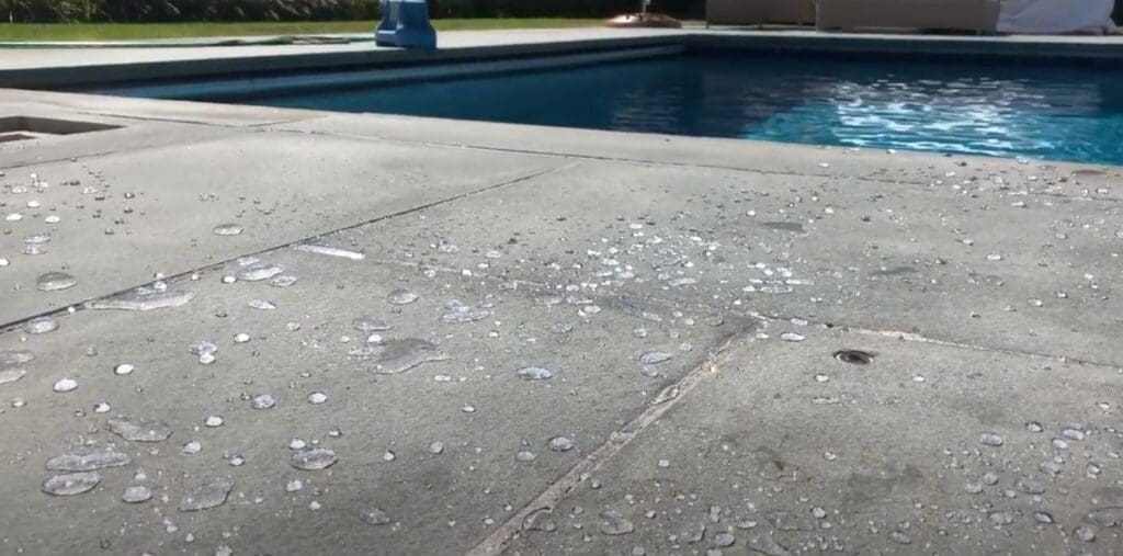 This image shows a close up of a bluestone paver patio with water beading up and not soaking into the bluestone due to the hydrophobic nature of paver sealers.